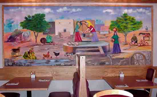 Hand-painted mural of North Indian village life on the dining-room wall.